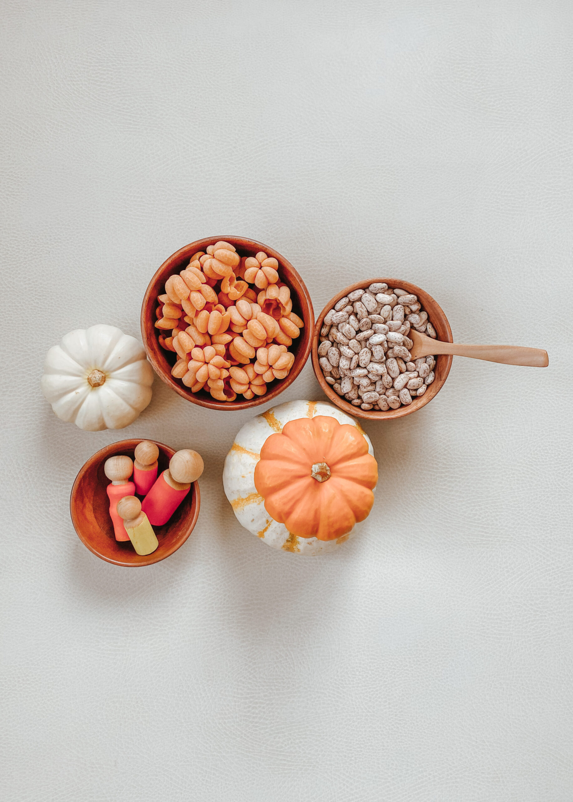 Fall sensory bin idea with small bowls, pumpkin pasta, pinto beans + nin peg dolls